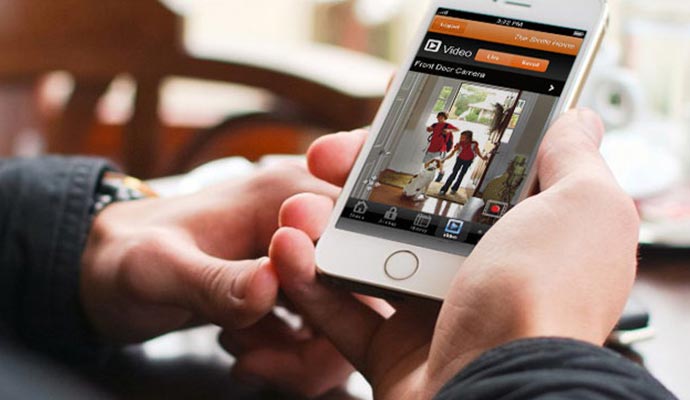 Man is holding mobile phone and monitoring home