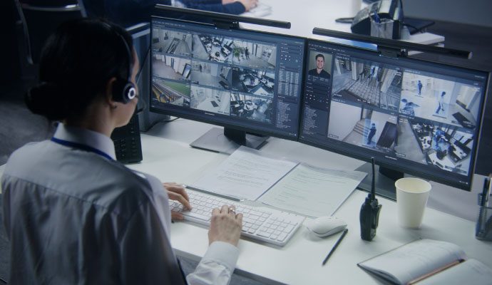 Security operator monitoring multiple surveillance camera feeds in a control room