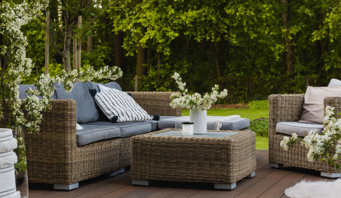 Outdoor wicker lounge set with greenery.